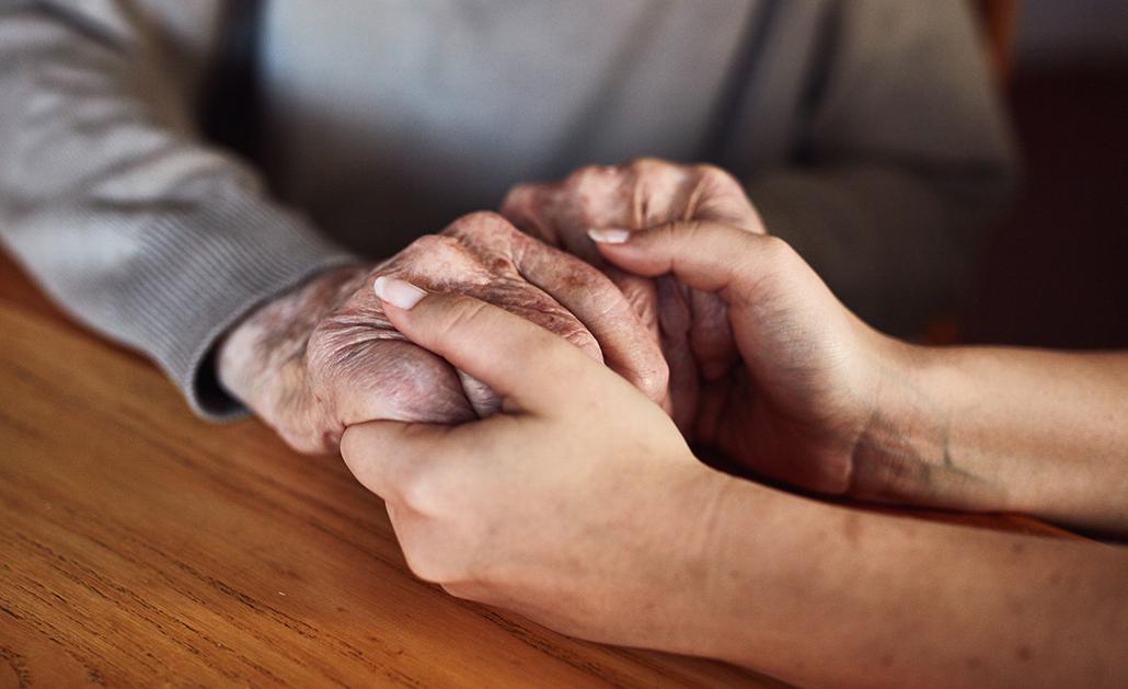 Two people, one older and one younger, holding hands